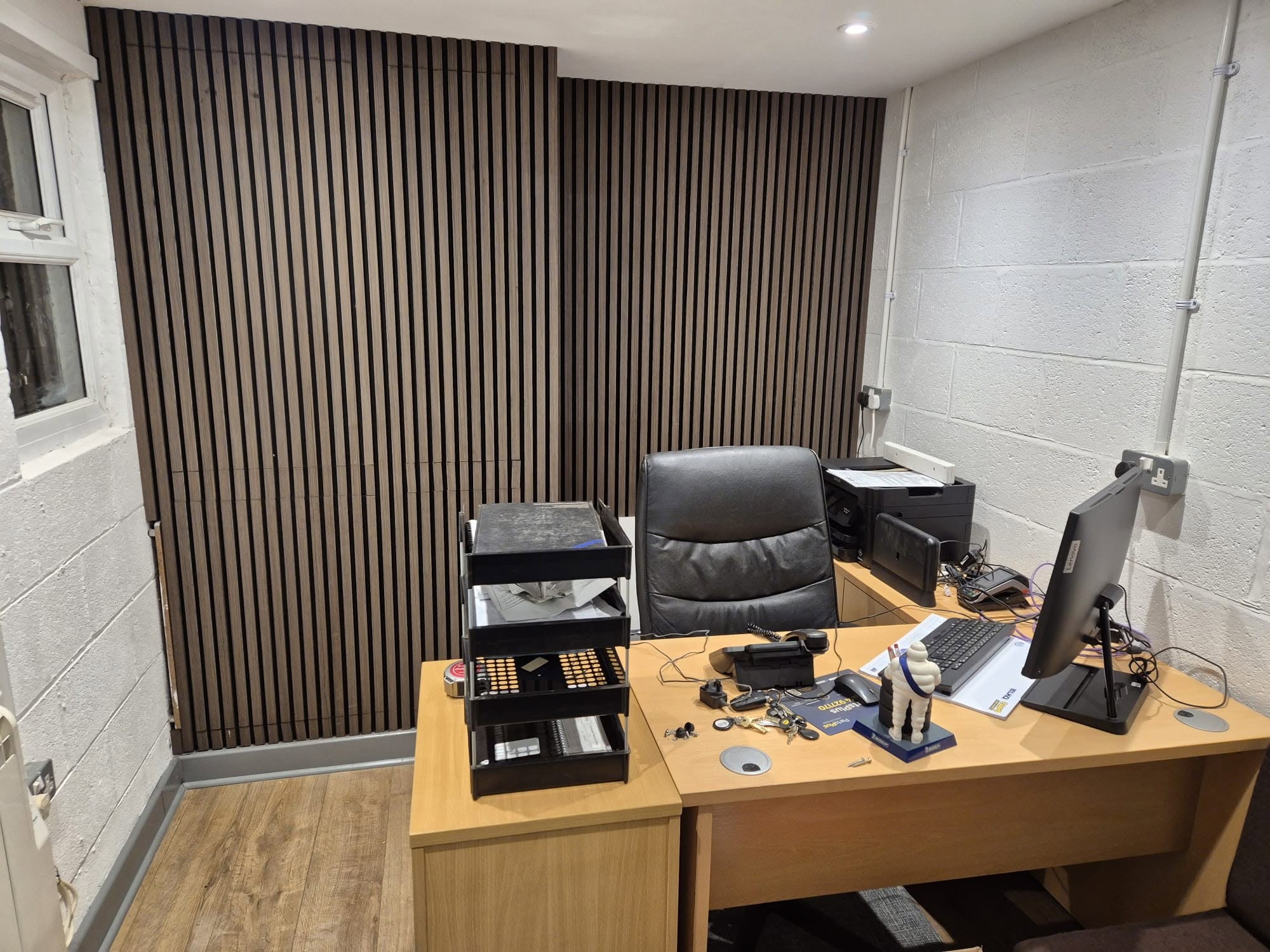 The new office with a slatted wood wall, a desk, a chair and a computer