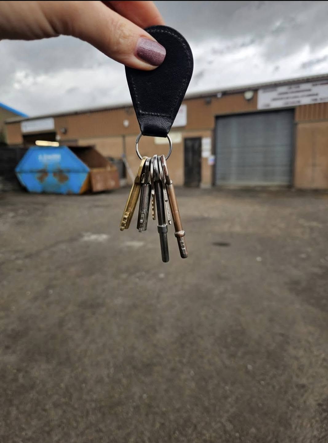 A set of keys on a leather fob held up in front of the new unit