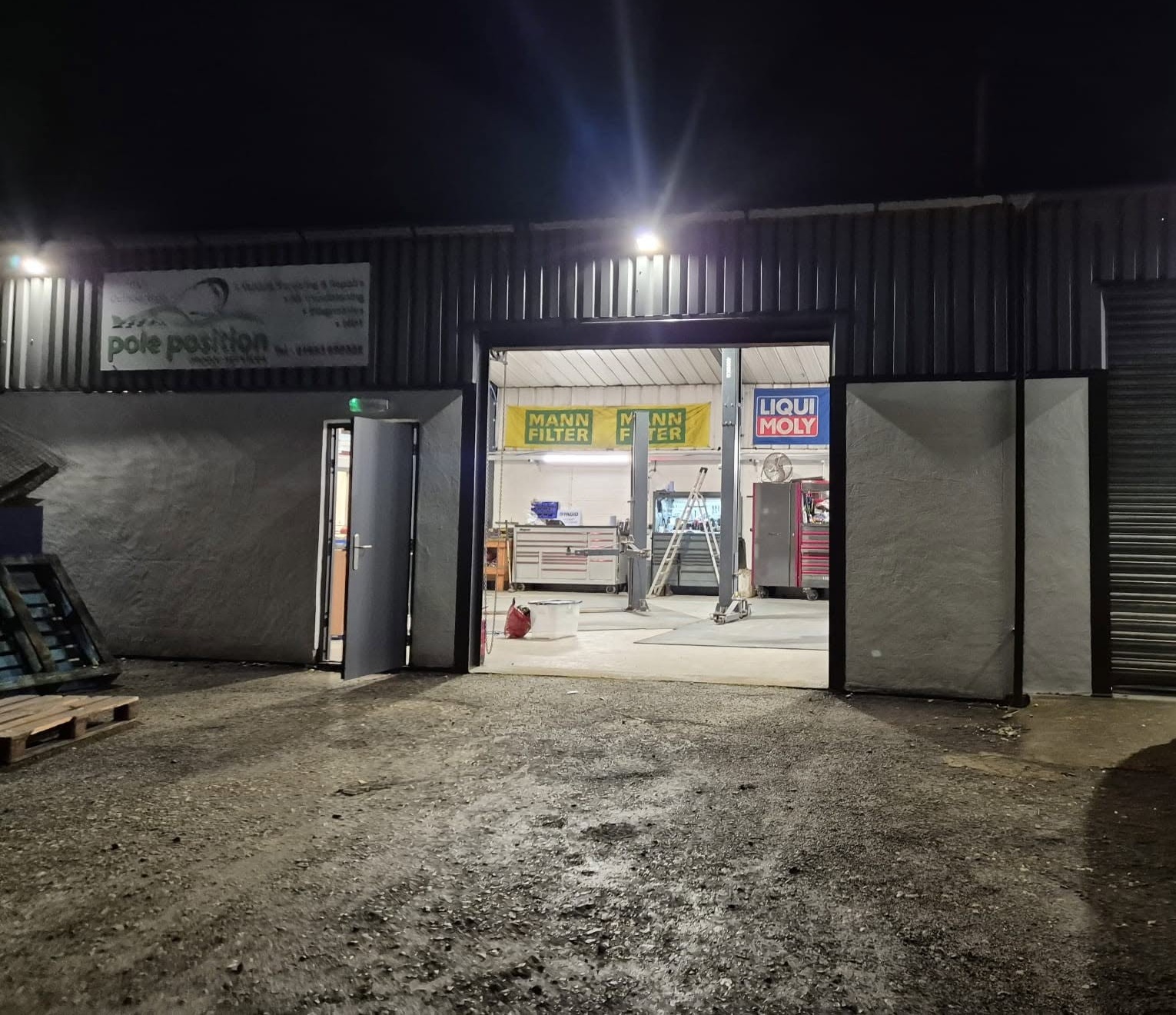 The new unit at night with its doors open, the workshop lit inside and the Pole Position sign on the wall