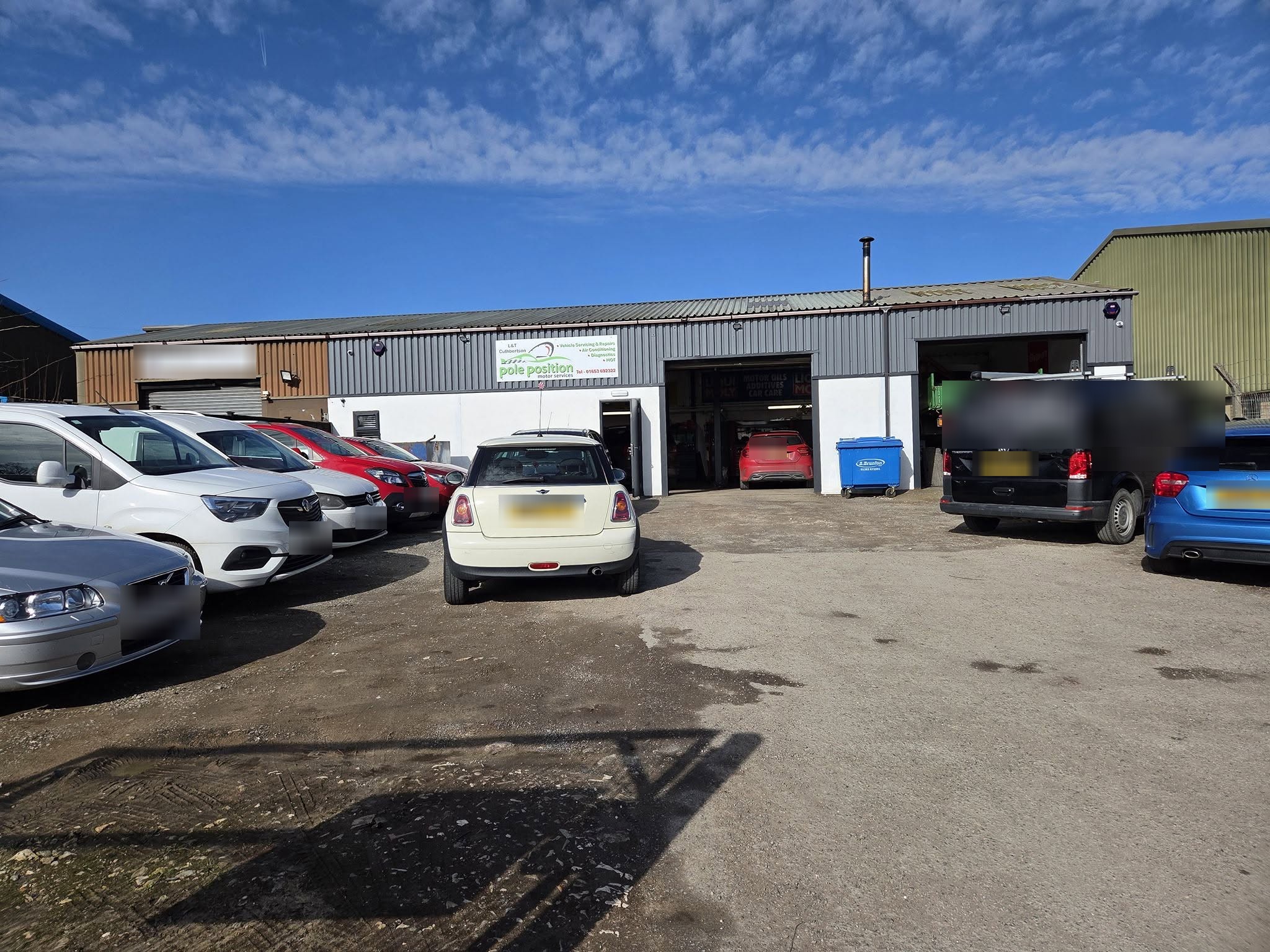 The front of our unit on Riccal Drive with the Pole Position sign, open workshop doors and customers' cars in the yard