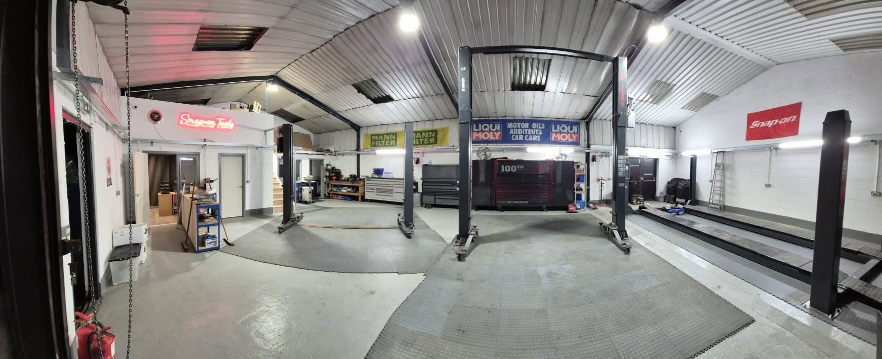 A wide panorama of the empty new workshop with its lifts, toolboxes and office