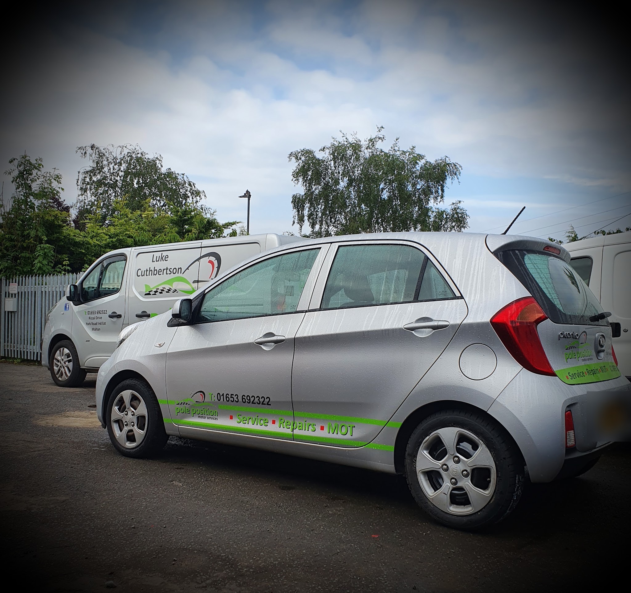 A silver Kia Picanto in green Pole Position livery parked in front of the Luke Cuthbertson van